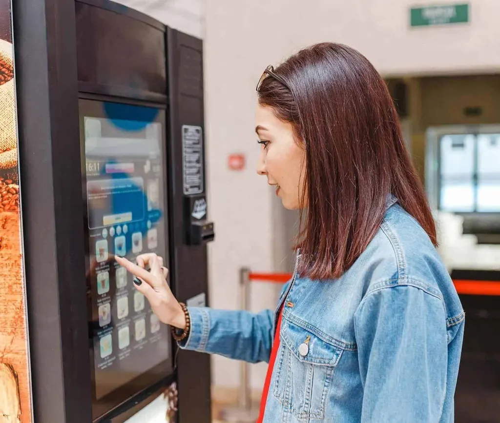 Utilisatrice choisissant sa boisson sur l'écran tactile d'une machine à café automatique